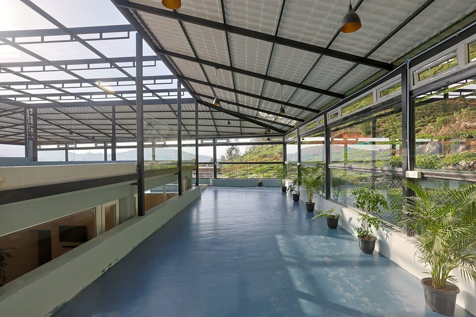 The banquet hall glazed to the roofline, with potted palms along the terrace edge