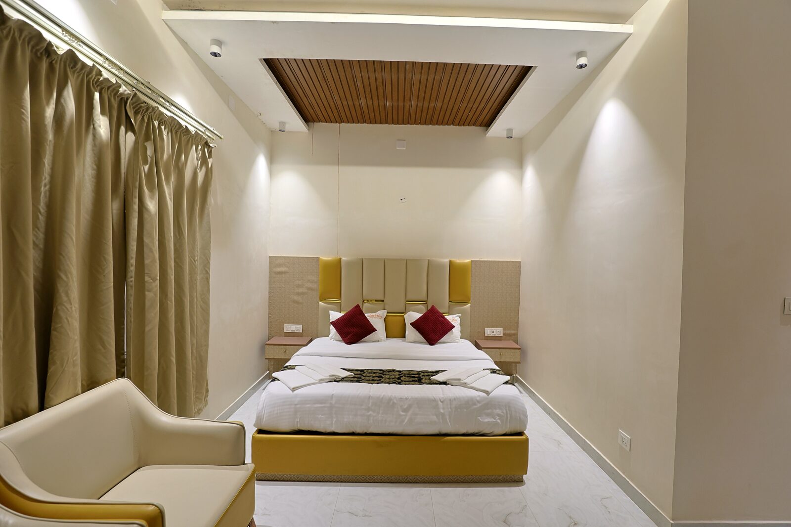 Guest room with a made-up king bed, armchair and a wood-slatted ceiling cove