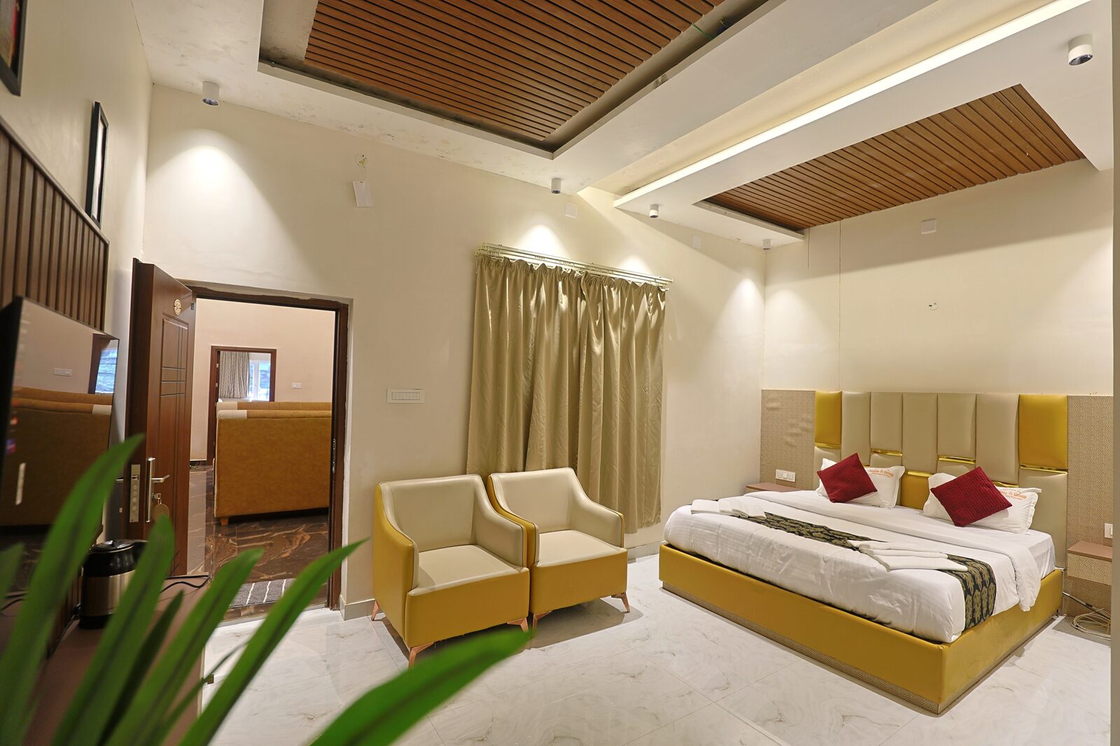 Guest room with twin beds, gold armchairs and a wood-panelled ceiling cove