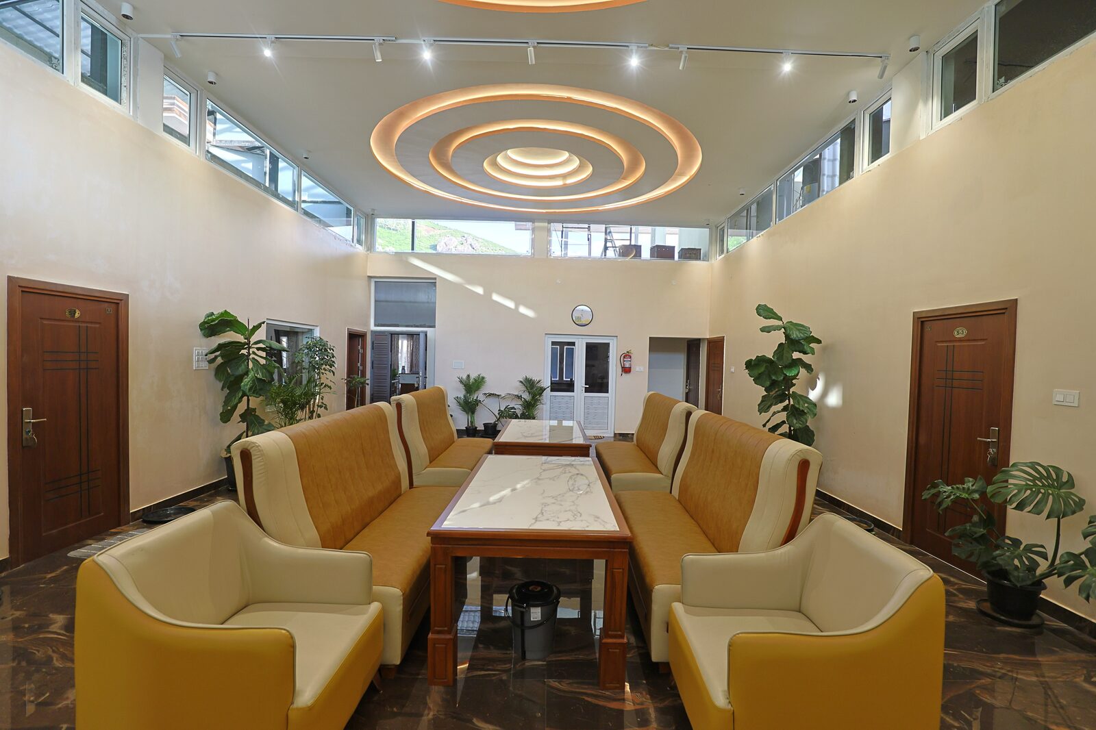 Reception lounge seating around a marble-topped table, framed by indoor plants
