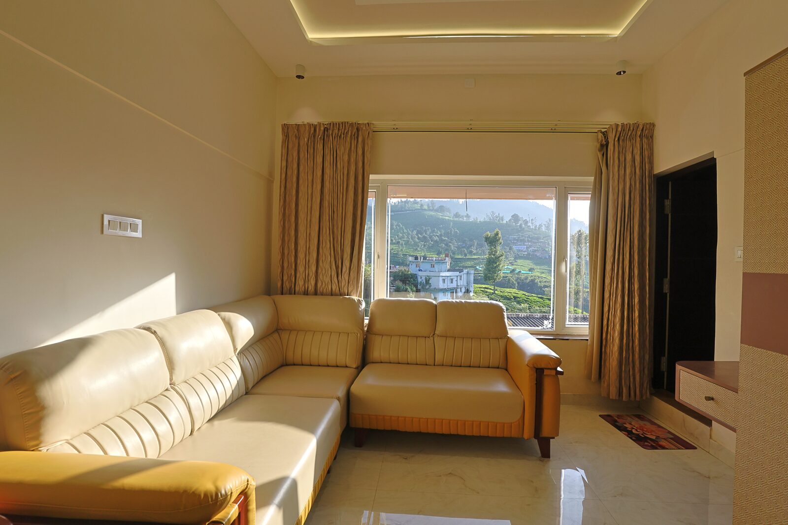Cream leather corner sofa beside a window looking down the valley