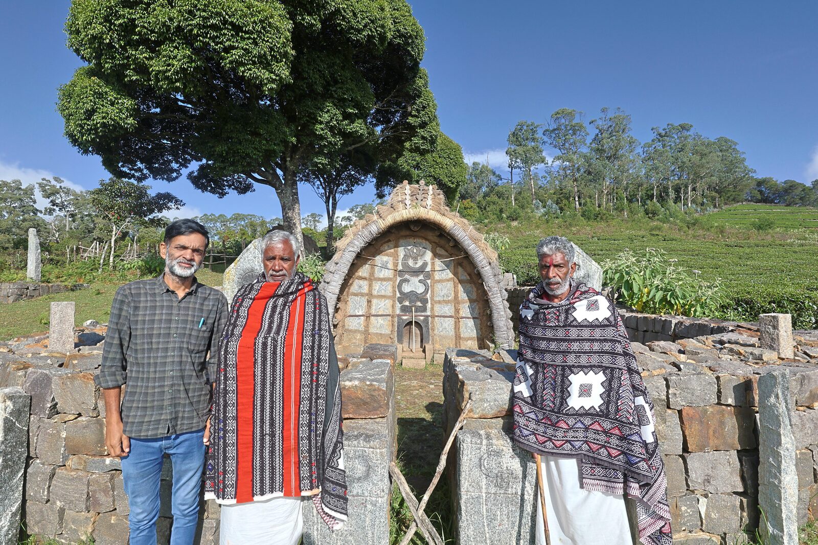 Toda elders in embroidered putukuli shawls outside a barrel-vaulted village hut